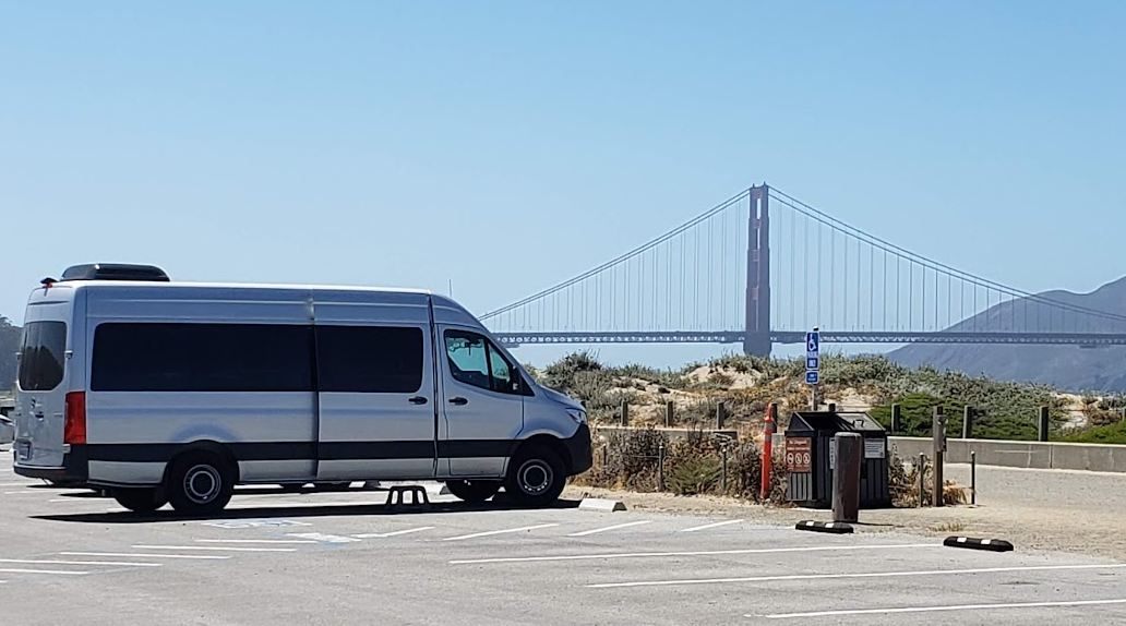 The silver Sprinter treatment van parked in a waterfront lot with the Golden Gate Bridge behind it
