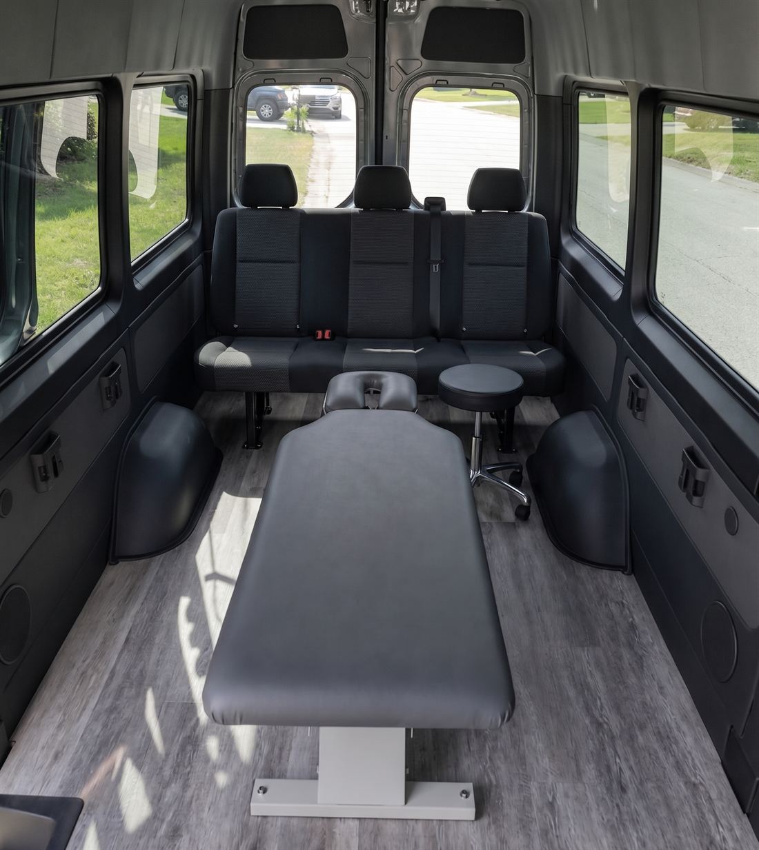 Inside the treatment van: a chiropractic adjusting table, stool, and bench seating with full standing headroom